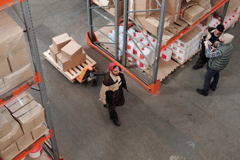 Team working in an industrial warehouse discussing and organizing inventory with pallets.